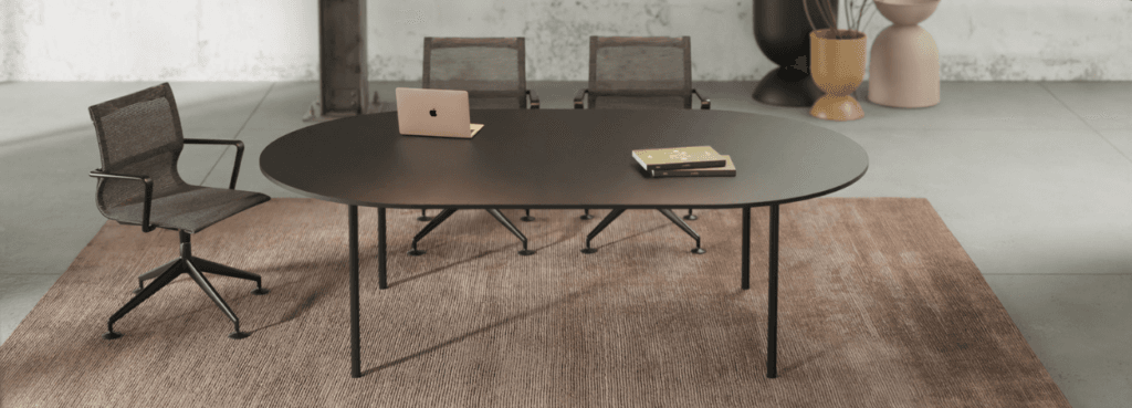 Alea Rendez-Vous table with chairs, laptop, and books on a brown rug. Modern office furniture.