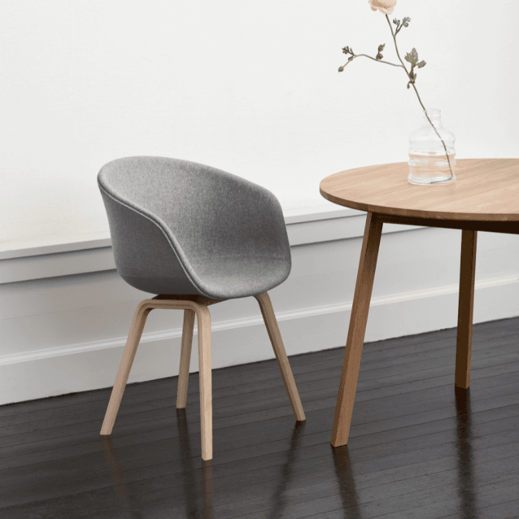 HAY AAC 23 chair. Gray, fully upholstered shell with a wooden base. Modern design.