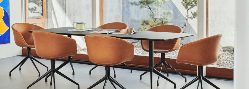 AAC 21 chair in tan leather with black swivel base around a table.