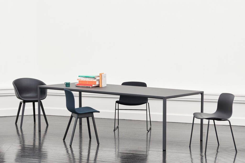Modern AAC 09 chairs in black and blue around a table. Steel frame, flexible design. Perfect for reception areas.