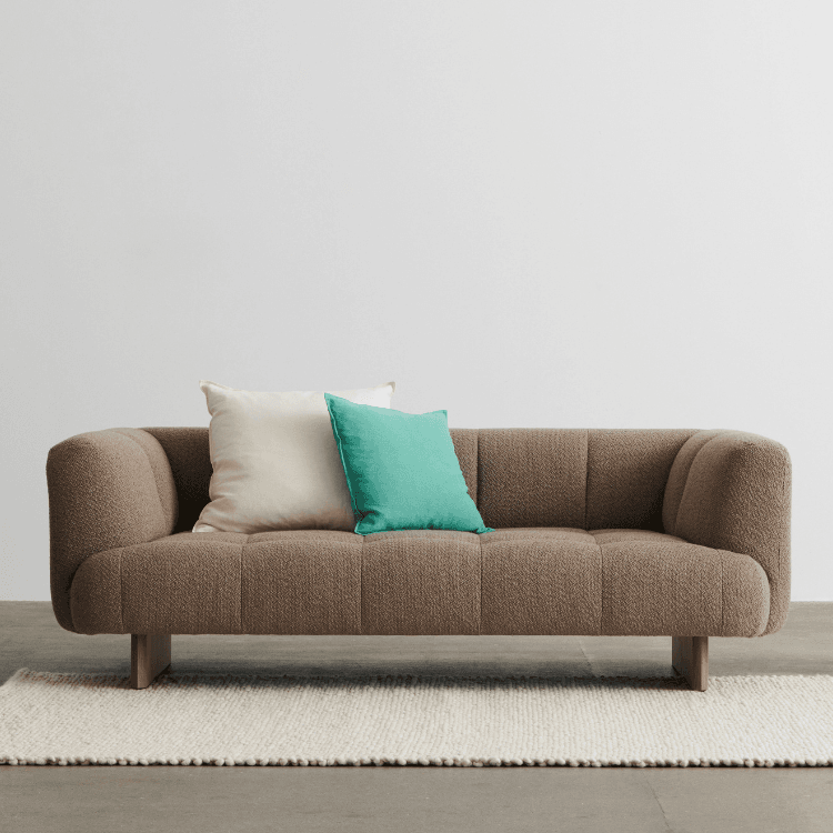 Quilton Lift sofa in brown fabric with pillows. Modern, elevated design with wooden legs.