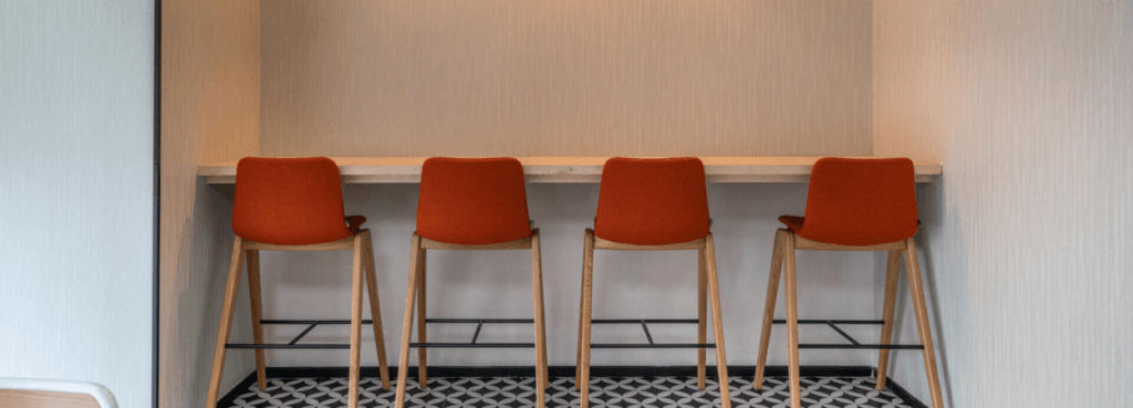 Four Ruby Wood Stools with orange seats and light wood legs.
