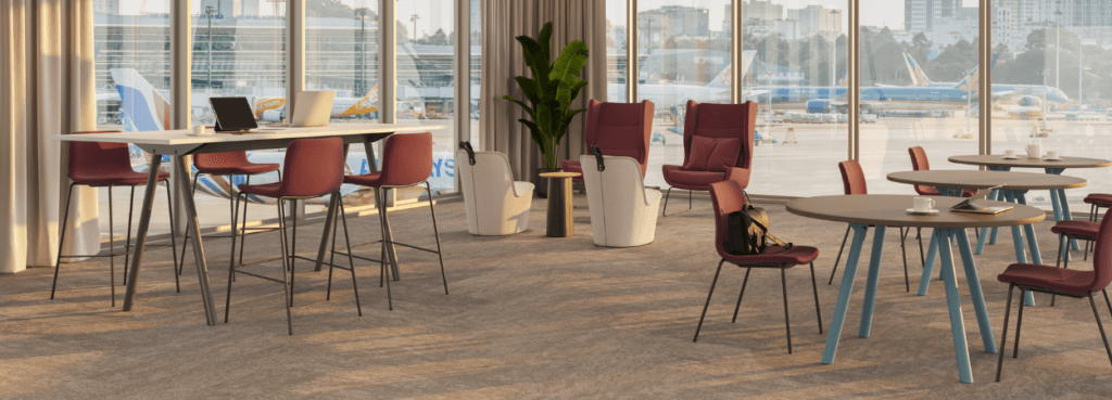 Modern workspace featuring NaughtOne Viv Stool seating in red, with tables and chairs in a bright, open airport lounge.