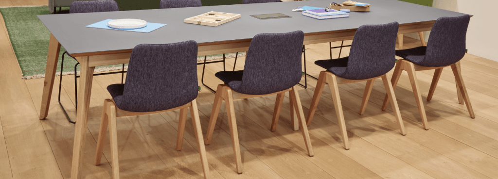 Modern Viv Wood Chair with a purple fabric seat and light wood legs around a table.