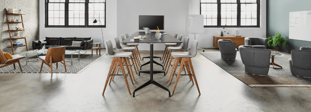 Modern office space featuring a NaughtOne Viv Wood Stool with a light gray seat and wooden legs, at a tall table.