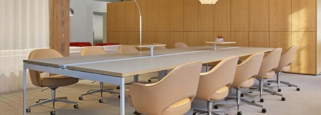 Saarinen Executive Chair by Knoll in tan leather, paired with a long conference table in a modern office setting.