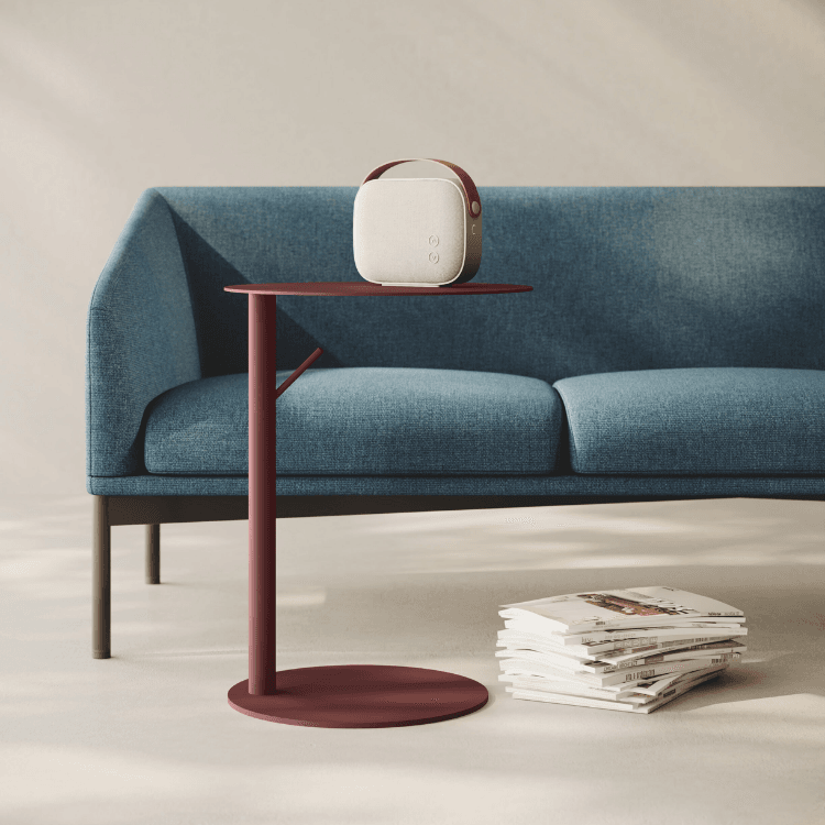 AUTO-DRAFT speaker on a modern red side table, styled with a blue sofa and magazines.