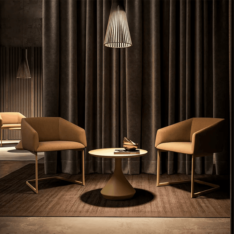 Modern Lamp Table. Round table with a lamp base, brown chairs, and a dark curtain backdrop.