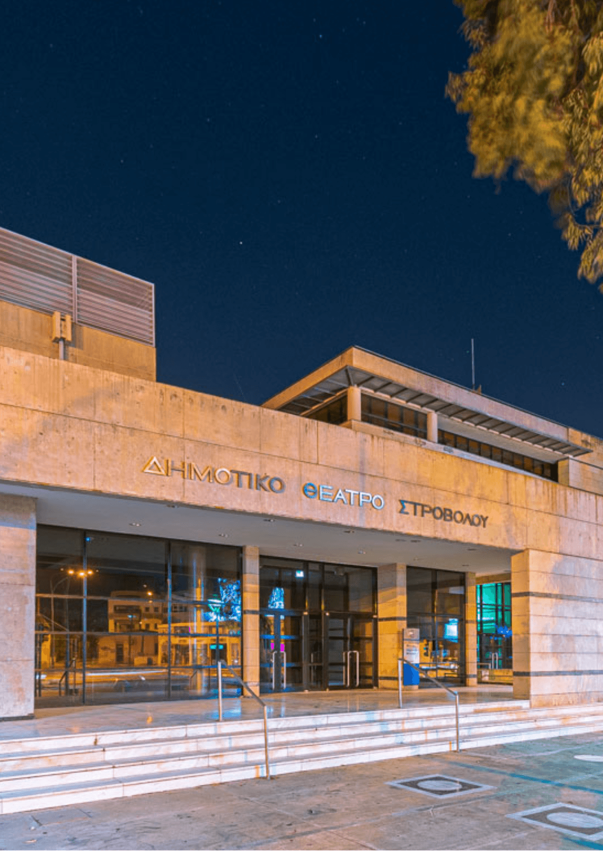 Strovolos Municipal Theater at the University of Cyprus. Modern architecture under a starry night sky. Building entrance with glass doors.