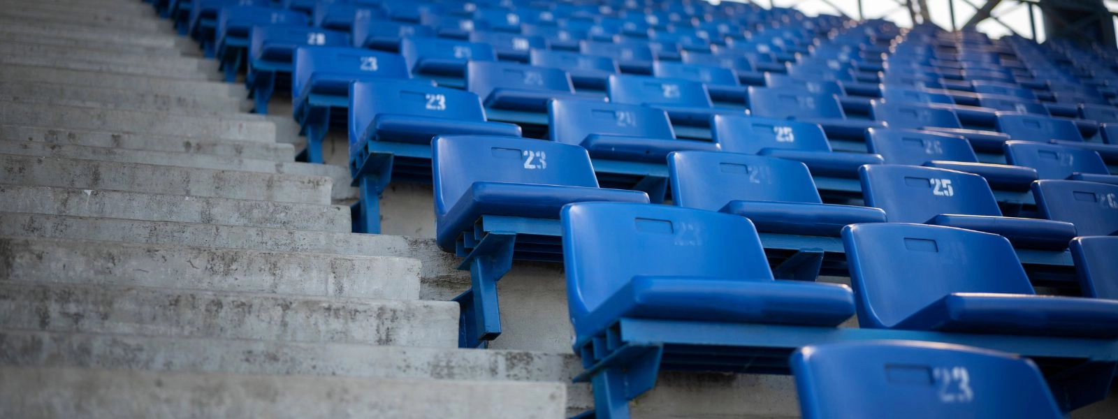 Rows of blue stadium seats with numbers, showcasing flexible seating arrangements.