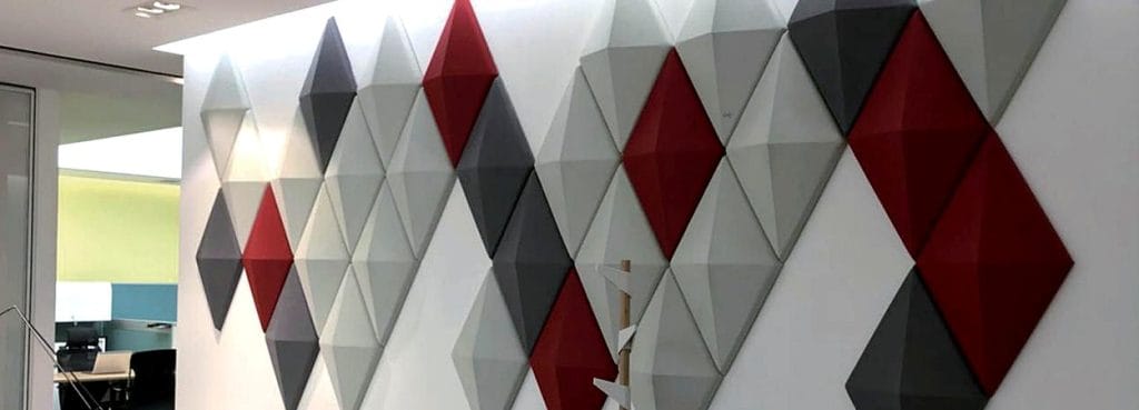 3D Diamond Grid acoustic panels in red, grey, and white felt featuring a bold, gem-cut relief on an office wall.