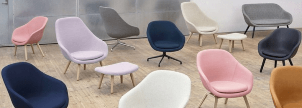 Collection of colorful AAL 81 chairs featuring diverse upholstery and varying base styles on a wooden floor.