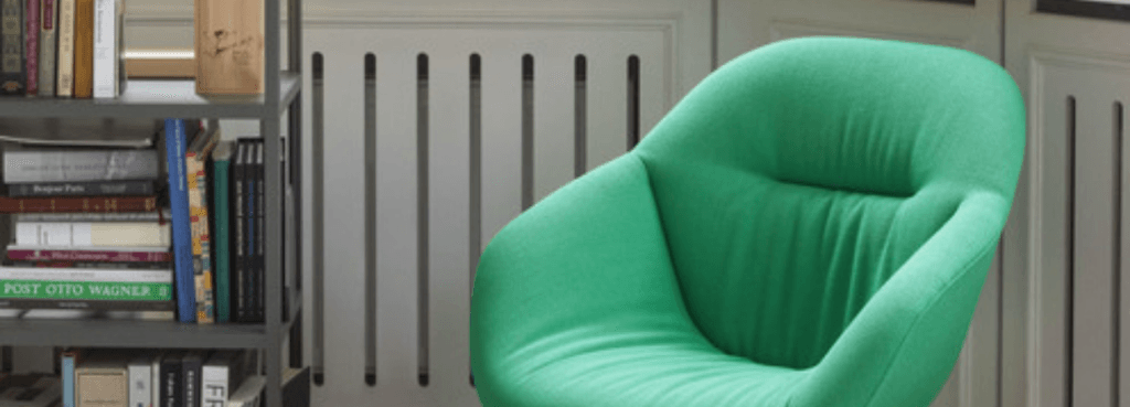 Vibrant emerald green AAL 82 Soft lounge chair with a quilted interior, positioned next to a home bookshelf.