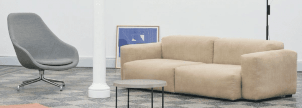 A grey AAL 83 Soft chair with a metal swivel base positioned beside a beige sofa in a contemporary interior setting.