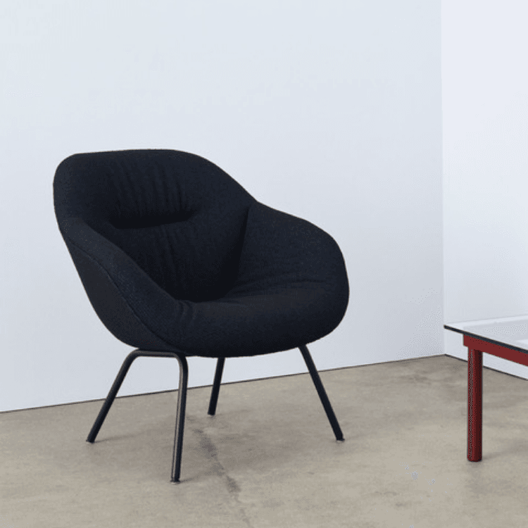 AAL 87 Soft lounge chair with dark blue quilted upholstery and slim black metal legs in a minimal room.