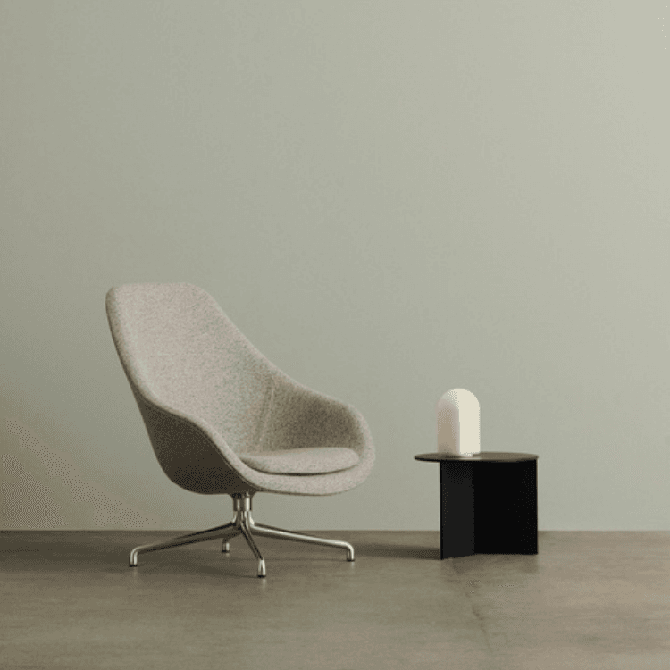 AAL 91 high-back lounge chair in grey upholstery on a swivel base, placed next to a small side table.