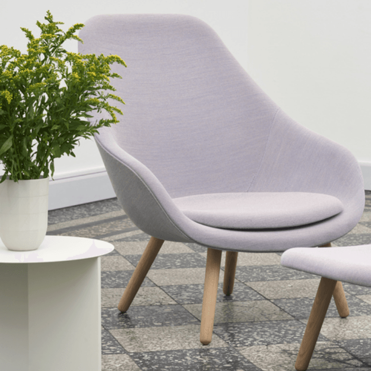 AAL 93 high-back lounge chair in soft light purple upholstery with a curved oak frame and matching footstool.