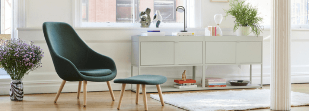 Dark green AAL 93 lounge chair with matching ottoman, featuring a curved shell and light oak wooden legs.