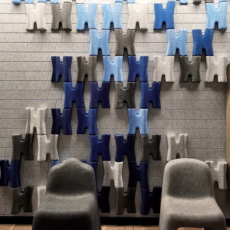 Arbor Weave sound-absorbing blocks form a textured, H-shaped interlocking pattern in varied blue and grey felt tones.