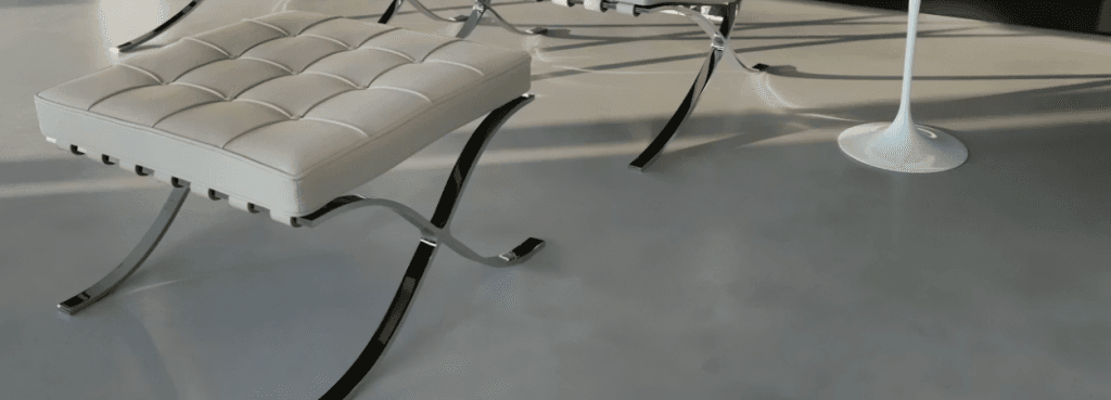 Minimalist cream Barcelona Stool with polished stainless steel base sitting on a sleek floor in natural light.