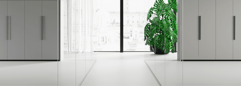 Light grey Box storage cabinets flanking a central corridor with full-height glass partitions and a large green plant.