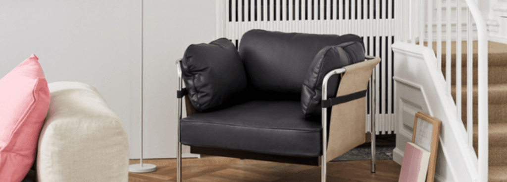 Minimalist black leather CAN 1 Seater armchair with exposed chrome frame and beige side panels in a bright home interior.