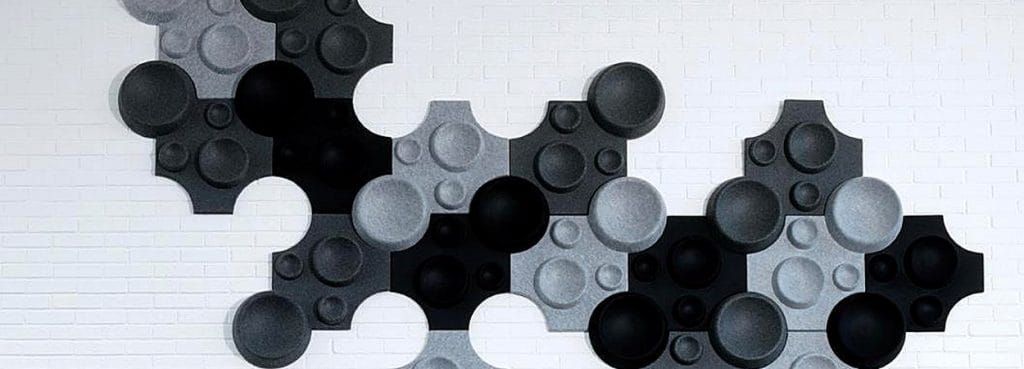 Crater Mini PET felt acoustic wall panels in a black and grey interlocking circular crater pattern.