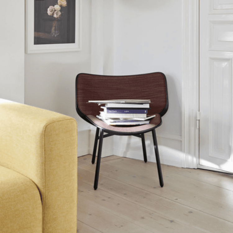 Dapper lounge chair with dark fabric upholstery and black frame in a bright, modern living room interior.
