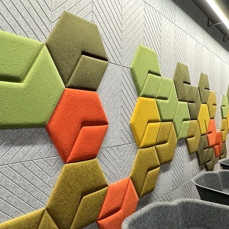 Multicolor felt Diag Hex acoustic panels mounted on a gray chevron patterned wall, creating a geometric 3D relief.