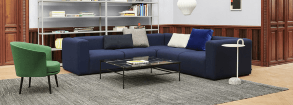 Vibrant green Dorso lounge chair placed in a cozy living room setting next to a dark blue modular sofa.