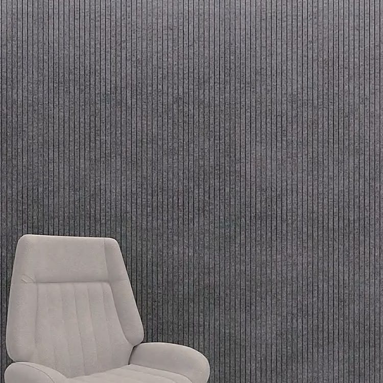 Charcoal grey Fluted Acoustic Slat Panel surface showing vertical felt ribs and narrow grooves behind a beige chair.
