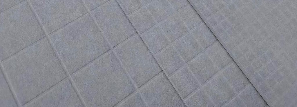 Close-up of a grey Grid Acoustic Panel made of textured PET felt with a precise square-grid embossed pattern.