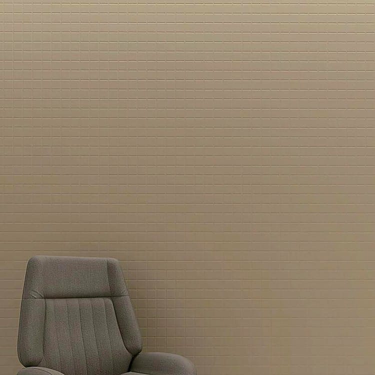 Minimalist beige Grid Acoustic Panel wall with a repeating square pattern, shown behind a modern grey armchair.