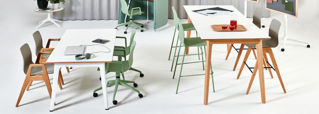 High-top and standard height white Dalby Table setups with light wood legs surrounded by sage green and brown chairs.