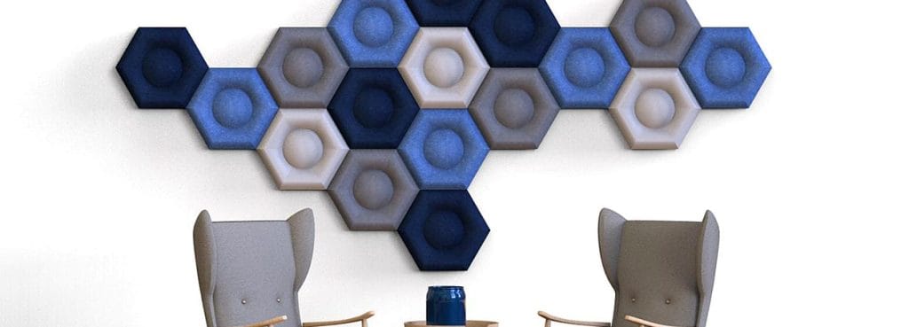 Hexa Core hexagonal PET felt acoustic panels in blue, grey, and cream arranged in a honeycomb pattern on a wall.