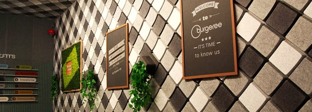 Keygrid Mini 3D acoustic felt wall panels in a black and white checkerboard pattern with wood-framed signage.