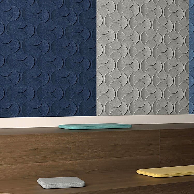 Lunar Crescent Small felt tiles in blue and grey mounted on a wall above a wooden bench with colorful cushions.