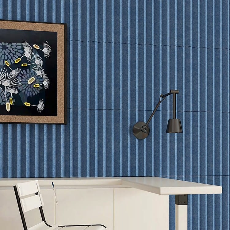 Deep blue Modu V acoustic wall tiles with vertical V-shaped ridges, featuring an adjustable lamp and framed wall art.