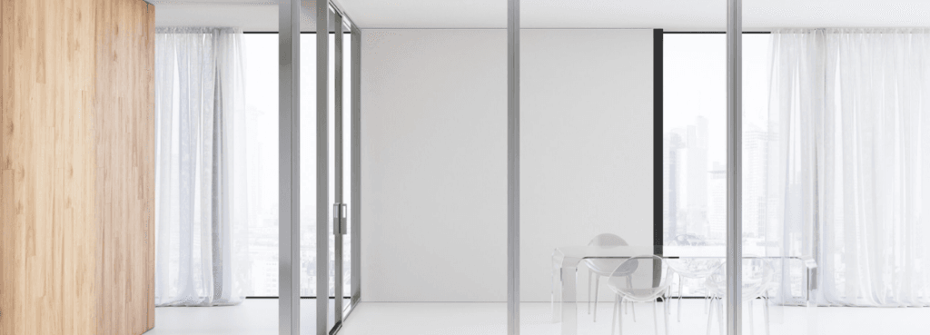 Over modular wall partition featuring light wood panels combined with clear glass and a structural silver frame.
