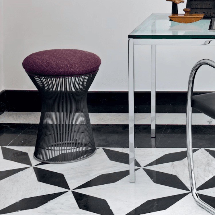 Platner Stool with dark wire base and purple upholstered cushion on a patterned marble floor.