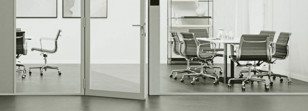 Pure AS System glass partition door creating a transparent divider between two modern, light-filled meeting rooms.