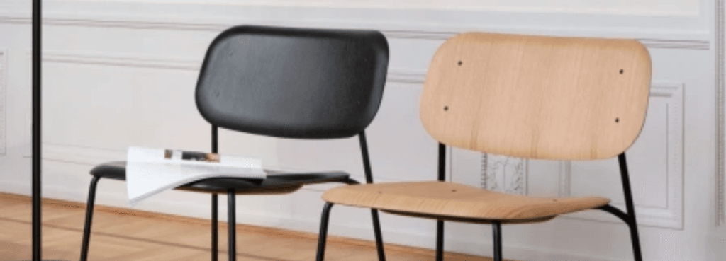 Contrast of black and oak Soft Edge 100 chairs with curved plywood seats and slender black metal frames in a room.