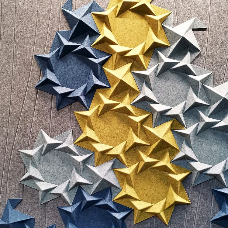 Multicolor Star Cluster acoustic panels featuring interlocking 3D felt star motifs in gold, grey, and navy blue.
