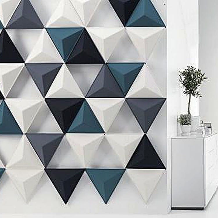 Tri Prism acoustic panels arranged in a sharp, spiked triangular lattice with a mix of deep navy, teal, and cream felt.