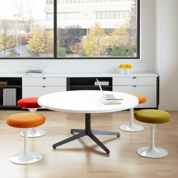 Tulip Stool with colorful padded cushions and iconic white pedestal base in a modern office setting.