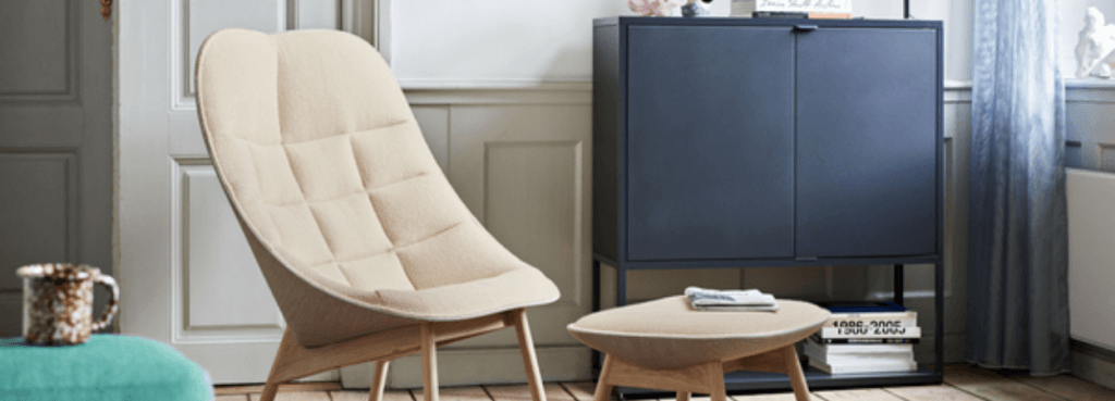 Uchiwa armchair and matching ottoman with light oak legs positioned in a home setting near a dark blue cabinet.