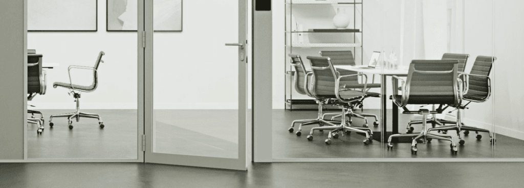 Ultra Silence System glass door partition installed in a modern office, featuring a hinged design and metallic frame.