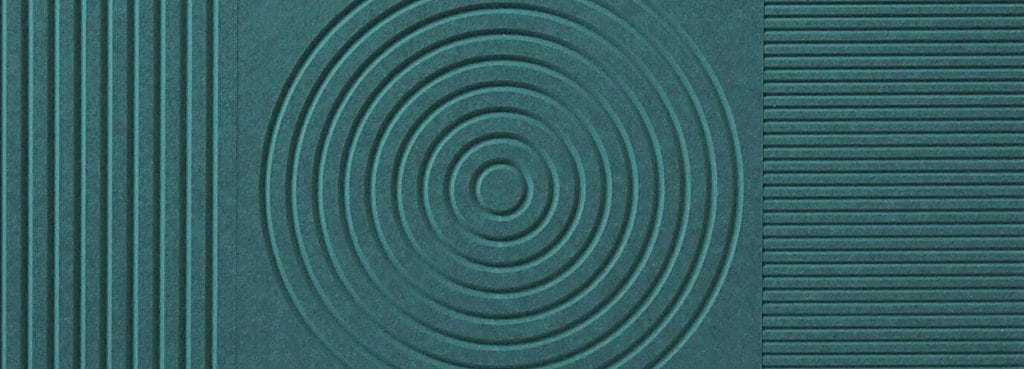 V-Flute Carved Acoustic Panel in dark teal PET felt featuring geometric patterns of lines and concentric circles.