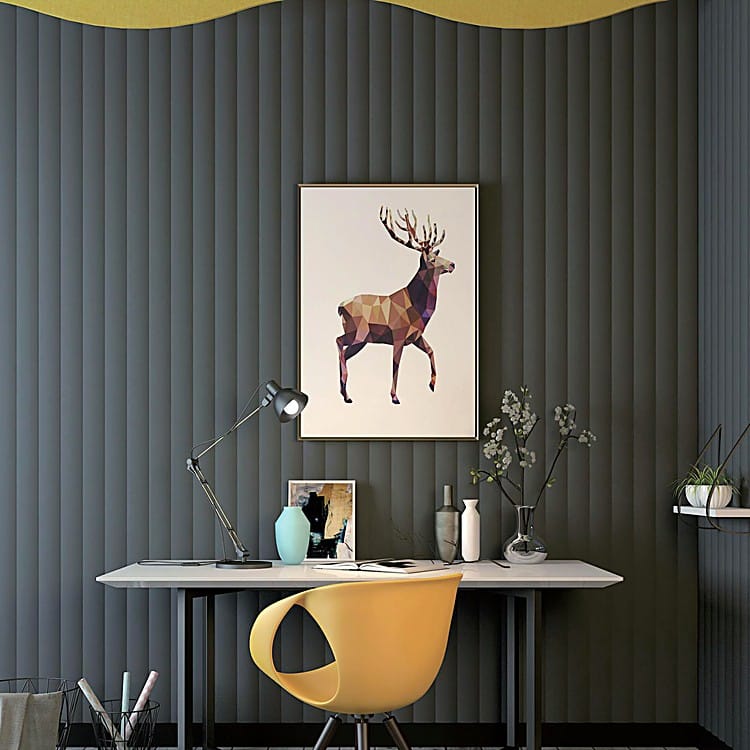 Valen Wave 70mm Acoustic Panel in dark grey with soft vertical ripples behind a desk, artwork, and a yellow chair.