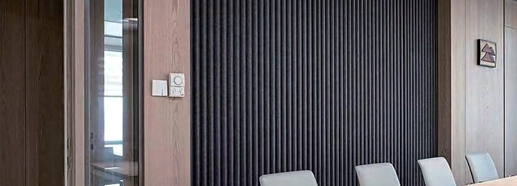 Close-up of a dark charcoal Wave-Patterned Acoustic Panel featuring a vertical sine-wave texture on a modern wall.